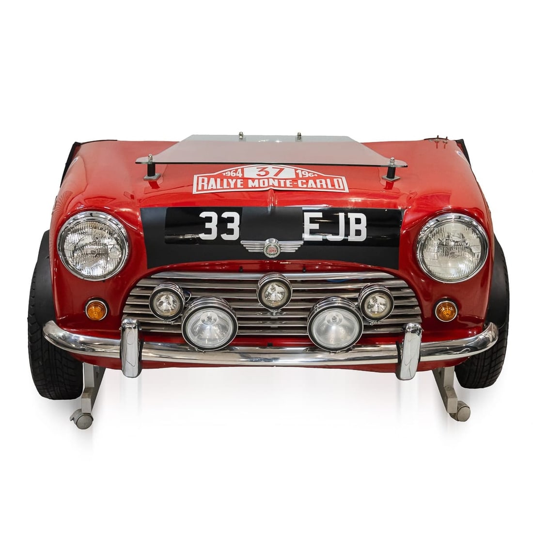 UNUSUAL 1964 MONTE CARLO RALLY REPLICA MINI FRONT END IN THE FORM OF A DESK: An Unusual 1964 Monte Carlo Rally Replica Mini Front End, in the form of a desk (modern), with glass shelf and a speedometer converted to a clock, the head lamps electrified, on a metal frame with