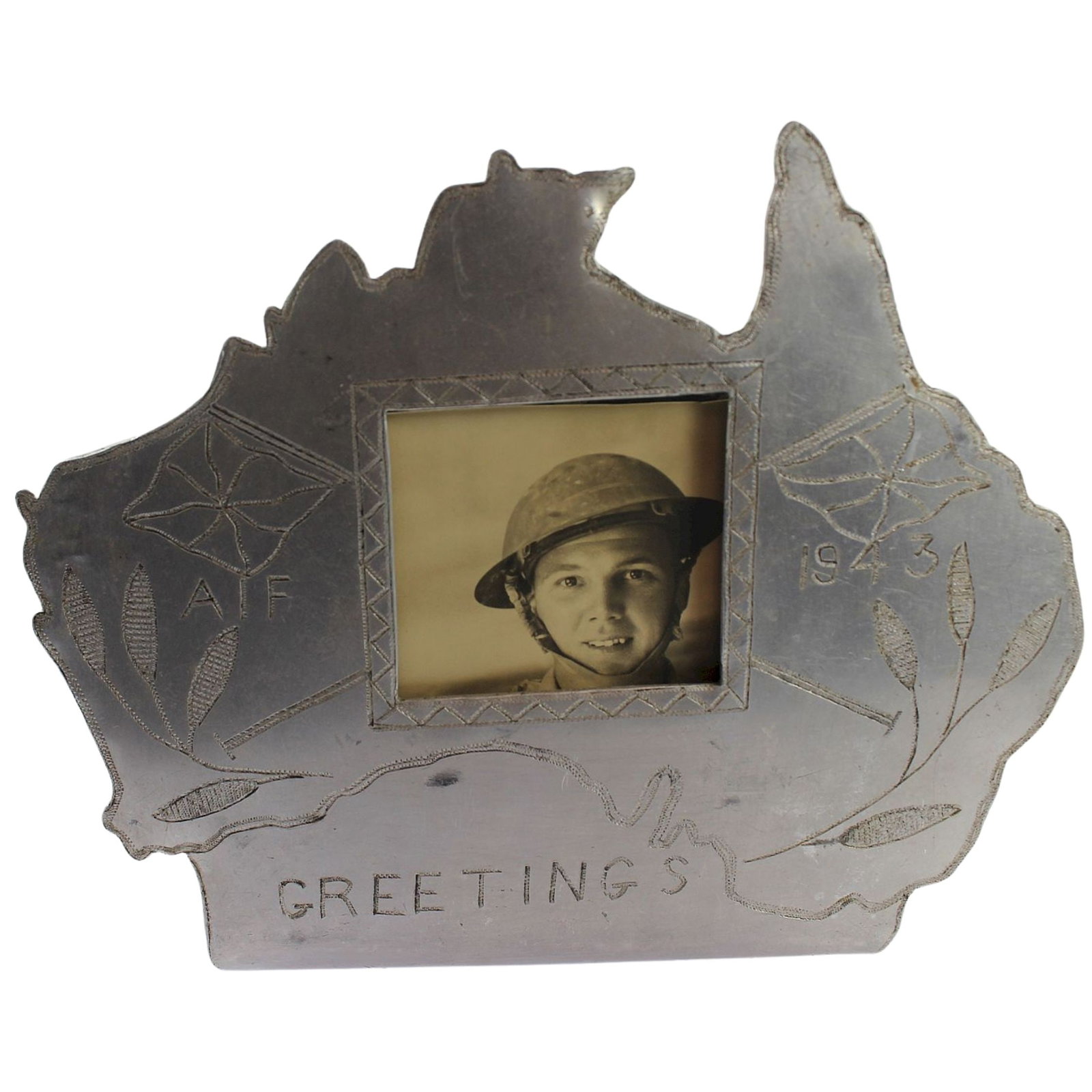 Australia - WWII Trench Art Photo Frame made from aluminium Aircraft Fuselage: A cut-out Map of Australia engraved 'AIF / 1943 / Greetings" A complementary piece to the preceding lot and could be combined as a pair of bookends. Size Stand 12cms Medium Collectibles