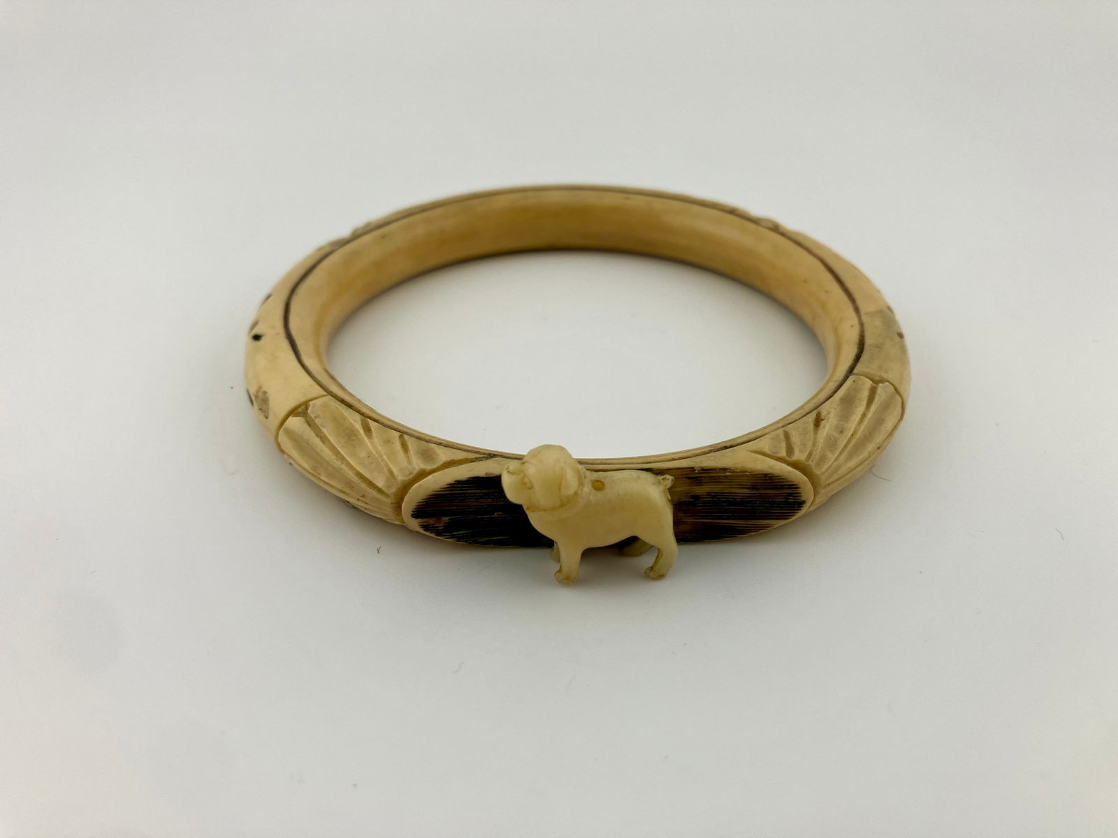 Vintage Carved Bone Bangle with Celluloid Figural Bulldog Dog: Vintage carved plastic (or bone) bangle with a figural celluloid bulldog. Fits wrists up to 7.5". Inside diameter is 2.5". 3/8" wide.