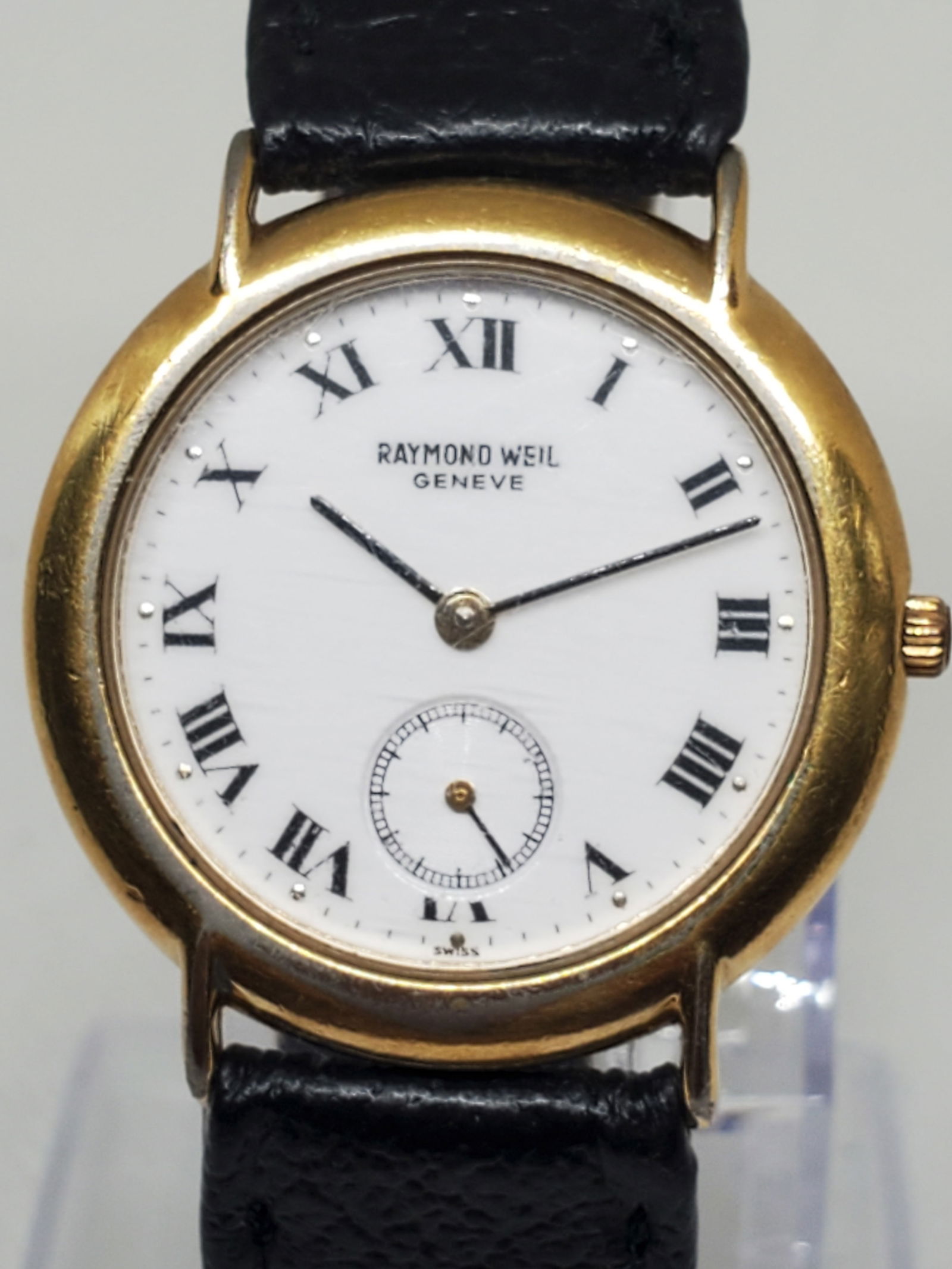 Vintage Raymond Weil Geneve 9808, 18K Gold Plated Quartz Dress Watch, 1980s: This refined Raymond Weil Geneve 9808 exudes timeless Swiss elegance with its 18K gold plated case, white dial, and classic Roman numeral hour markers. The seconds sub dial adds sophistication, while