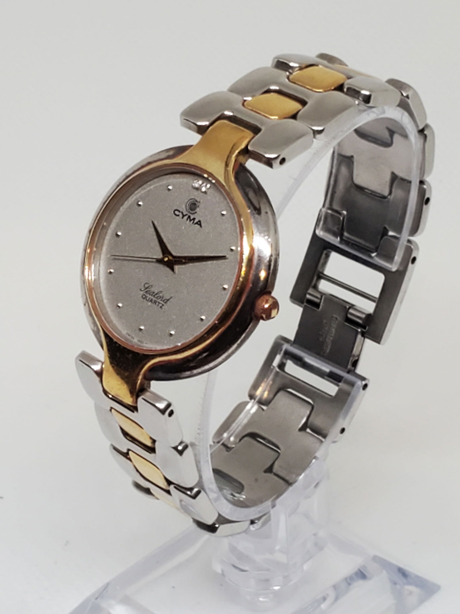 Cyma Sealord Dul Tone Watch, year 1980s: Cyma Sealord 411 in working condition, a watch that embodies elegance and timeless prestige. With its quartz movement and a sleek 1.25" (32 mm) circular gray dial adorned with diamond accents, this pi