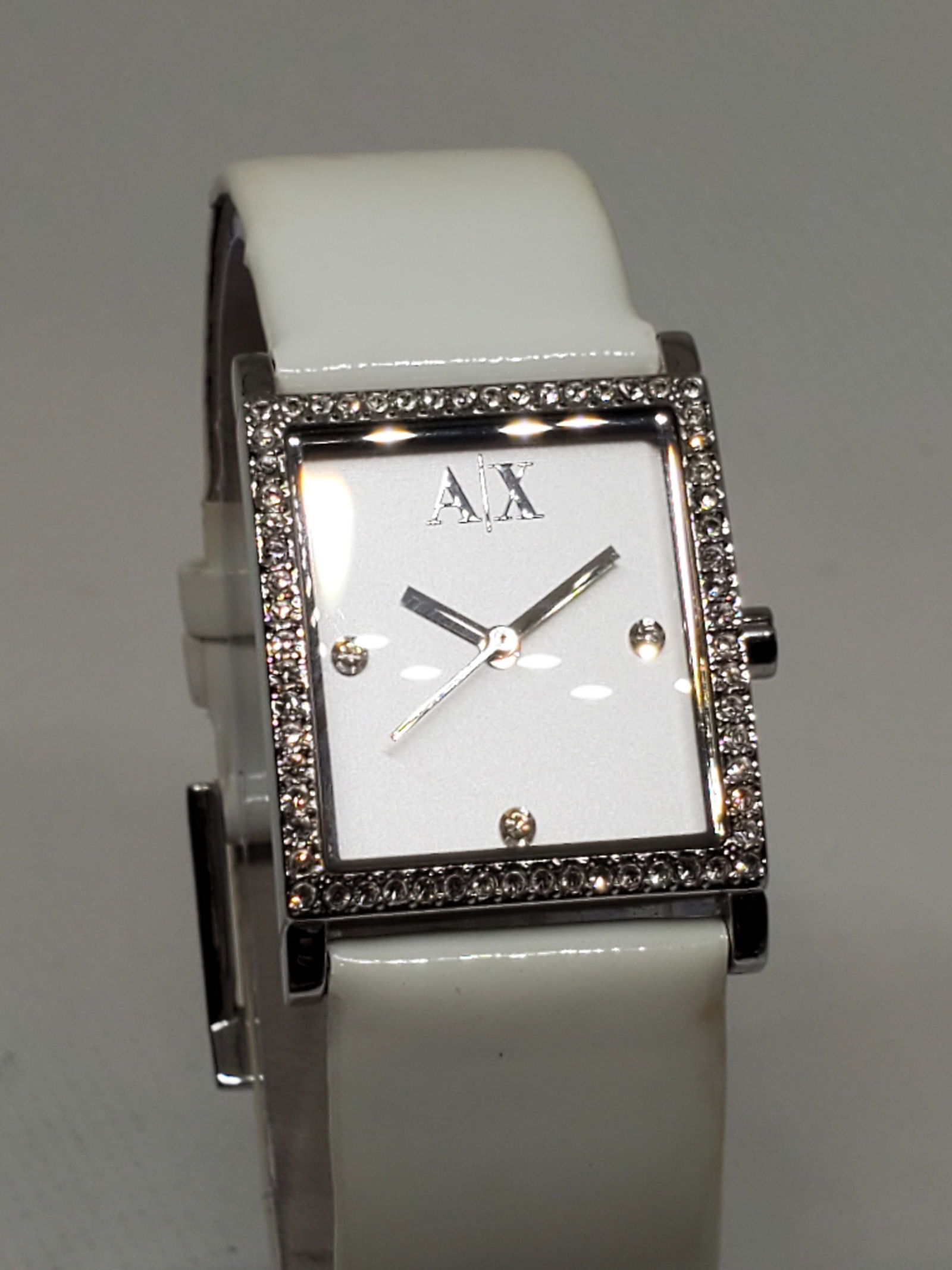 Armani Exchange Tank Silvertone Watch, 2000s: Armani Exchange AX 4068. This elegant tank style watch in working condition stands out with its distinctive silver tone case and stunning crystal bezel, creating a radiant frame for the sleek white di