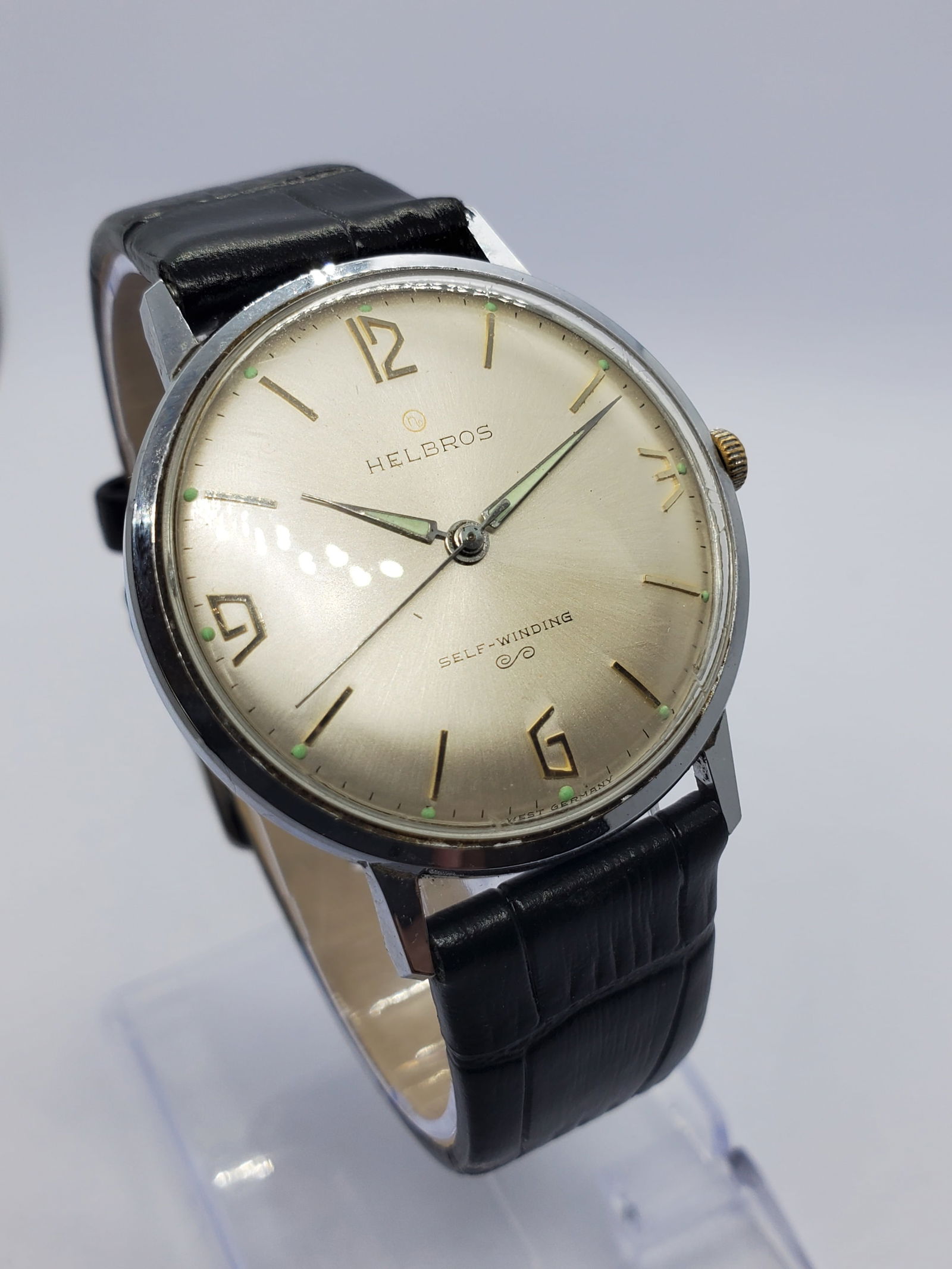Vintage Helbros Invincible Automatic Swiss Dress Watch Starburst Dial, 35mm, 1958 to 1965: This vintage Helbros Invincible automatic watch showcases understated mid century elegance with a refined silver tone case and a beautiful silver starburst dial that catches the light with subtle soph