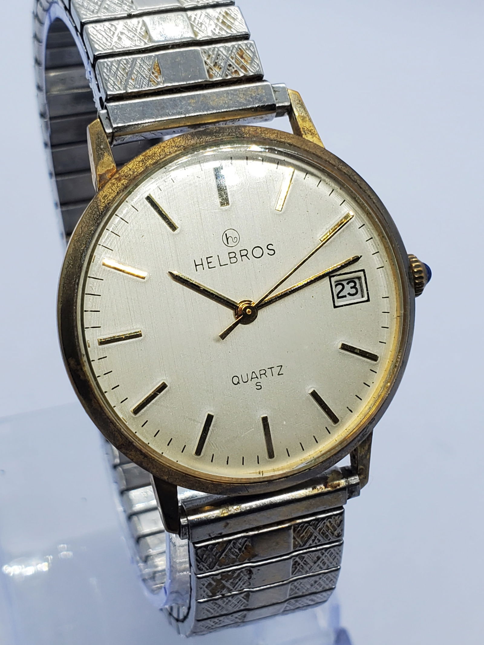 Vintage Helbros Quartz S Gold Tone Dress Watch Date 34mm Classic, 1980s: This Helbros Quartz S dress watch reflects understated elegance with a refined gold plated case and a light silver dial featuring a fine vertical brushed finish that adds depth and vintage character.