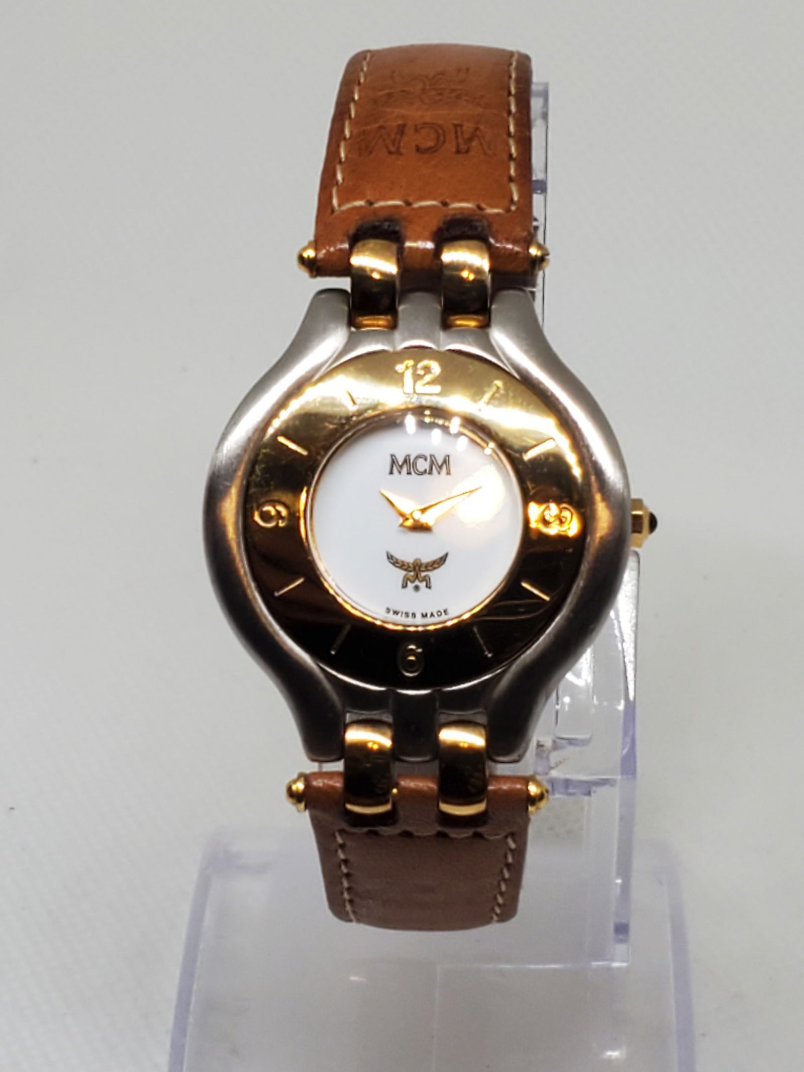 MCM Brushed Metal Gold Plated Bezel Ladies Watch, 1990s, Working: Elevate your collection with this MCM Swiss made quartz dress watch running , a refined blend of luxury and vintage elegance. Featuring a brushed metal case, gold plated bezel, and a clean white dial
