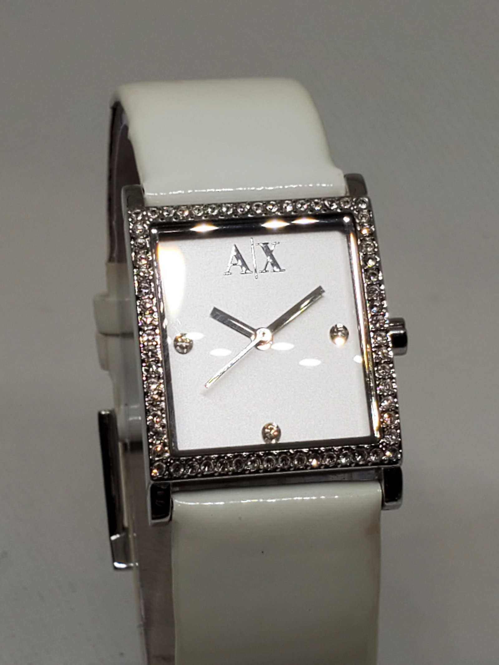Armani Exchange Tank Silvertone Watch, 2000s, Working: Armani Exchange AX 4068. This elegant tank style watch in working condition stands out with its distinctive silver tone case and stunning crystal bezel, creating a radiant frame for the sleek white di