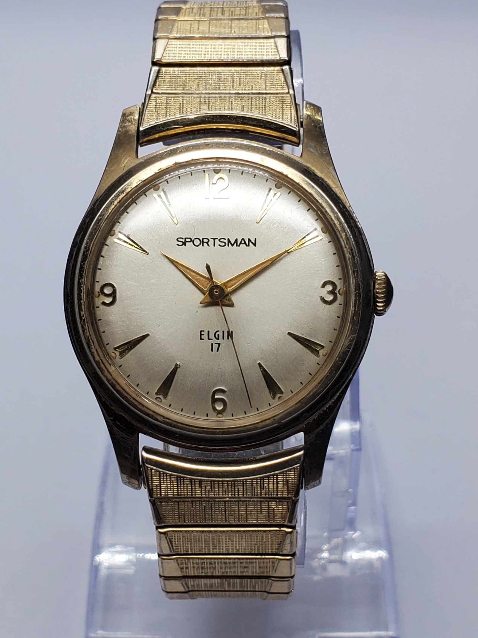 Elgin Sportsman Manual 17 Jewels Gold Plated Watch, 33mm, 1955 to 1965, Working: This classic Elgin Sportsman manual wind dress watch embodies mid century elegance with its 33 mm gold plated case, refined silver dial, and warm gold tone markers that create a balanced and timeless 