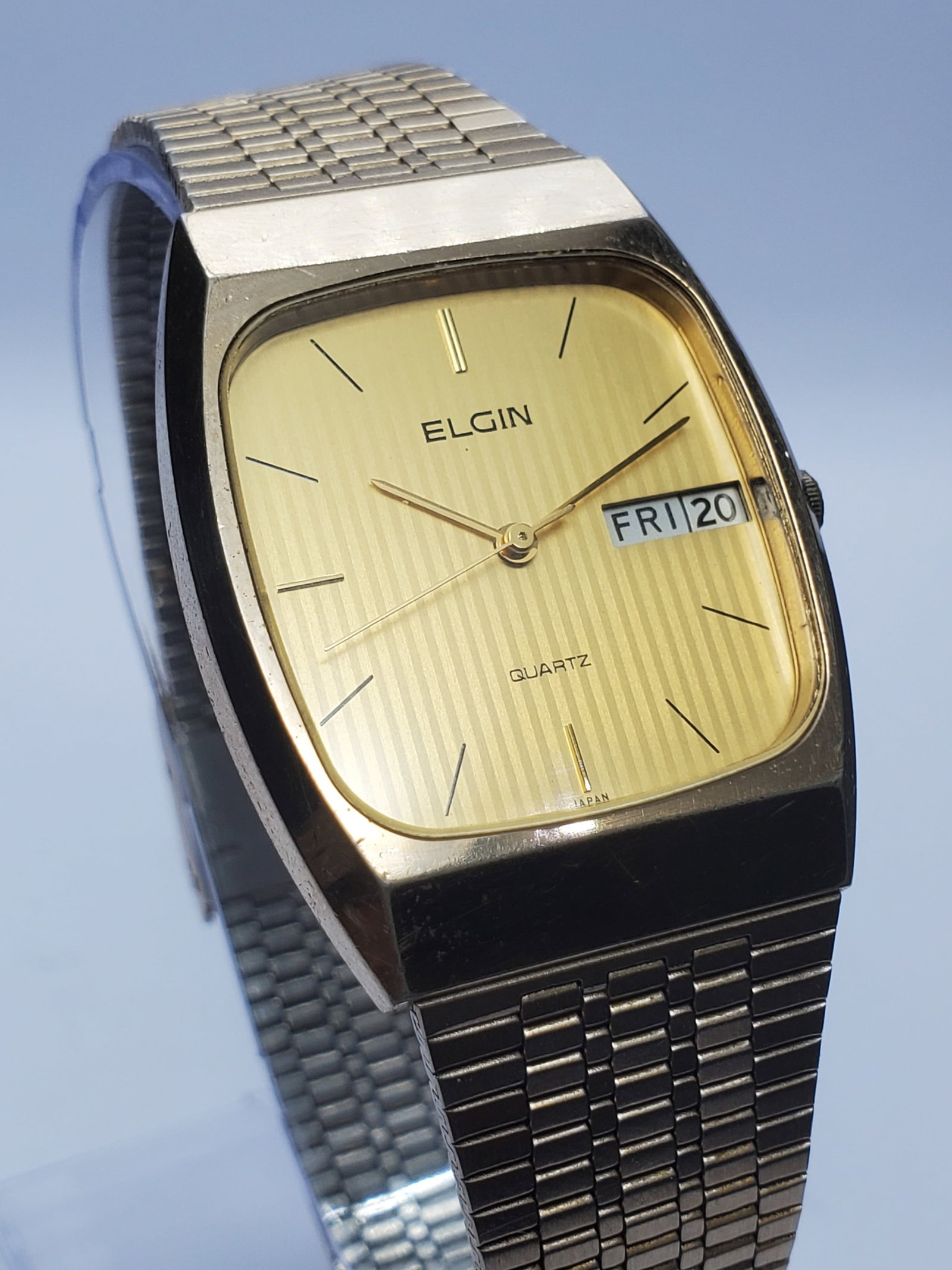 Elgin Gold Tone Quartz Day Date Vintage Dress Watch, 29x36mm, 1980s, Working: This elegant vintage Elgin FKA 163 quartz dress watch reflects timeless sophistication with its gold plated 29 mm by 36 mm case and refined gold pattern dial, enhanced by clean baton markers and a pra