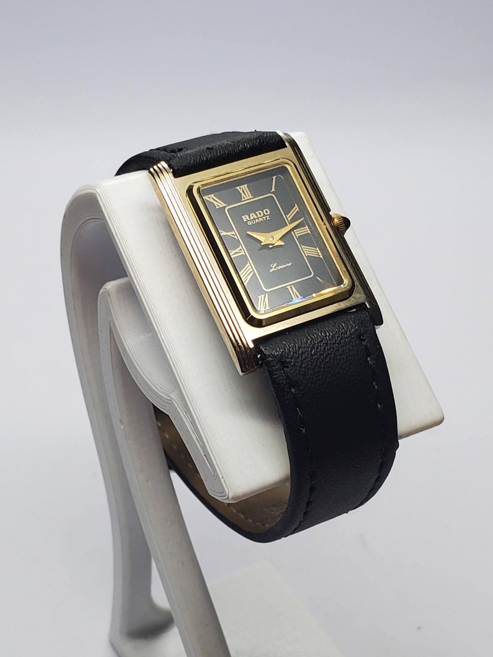 Vintage Rado Louvre Tank Swiss Watch, 19x22mm, 1980s, Working: Elegant and unmistakably refined, this vintage Rado Louvre Quartz dress watch reflects the innovative spirit of one of Switzerland?s most respected watchmakers. Founded in 1917 in Lengnau, Switzerland