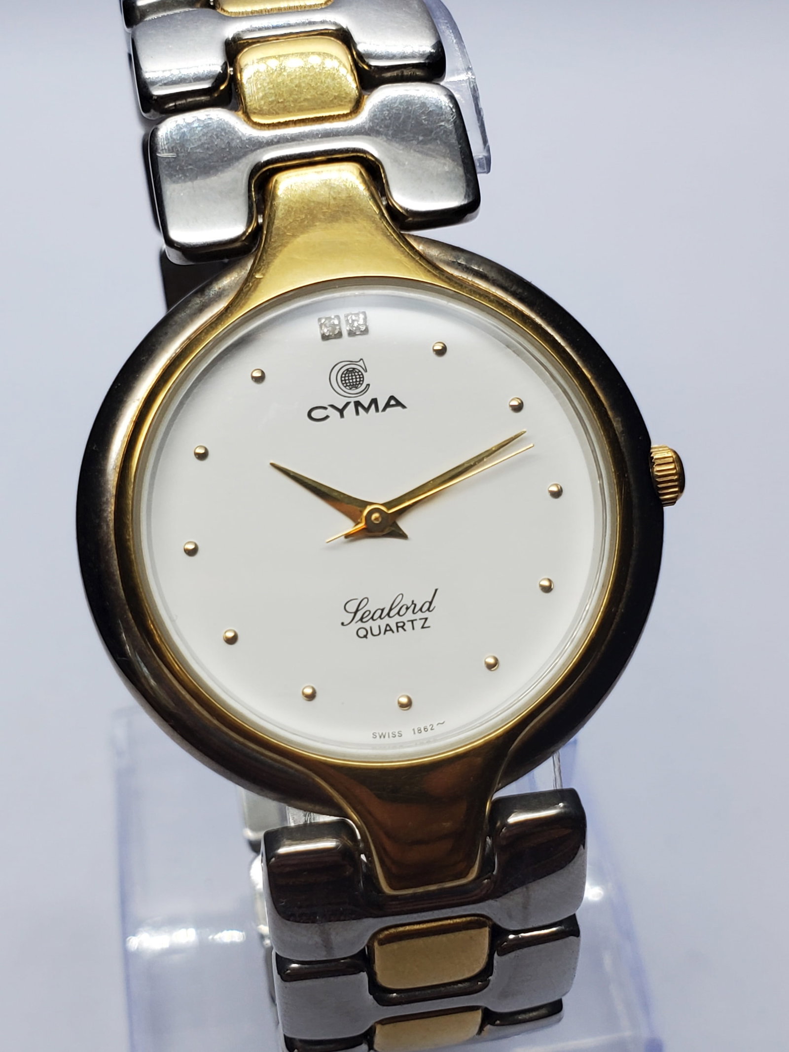 Vintage Cyma Sealord Dual Tone Watch With Diamonds, 32mm, 1990s, Running: Experience timeless Swiss elegance with this Cyma Sealord 411 quartz dress watch, a refined example of the craftsmanship that has made Cyma respected among collectors for generations. Founded in 1862 