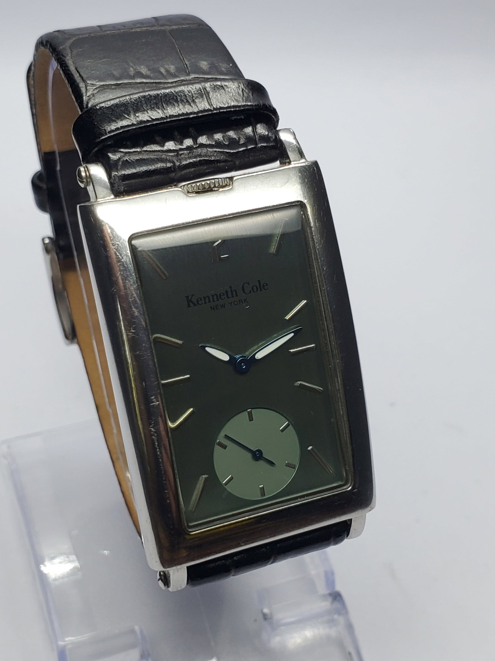 Vintage Kenneth Cole Olive Green Tank Watch, 28x41mm, 2000s, Running: This Kenneth Cole U54 04 KC1186 quartz dress watch showcases modern elegance with a refined tank style silver tone case paired with a striking olive green sunburst dial that shifts beautifully under l