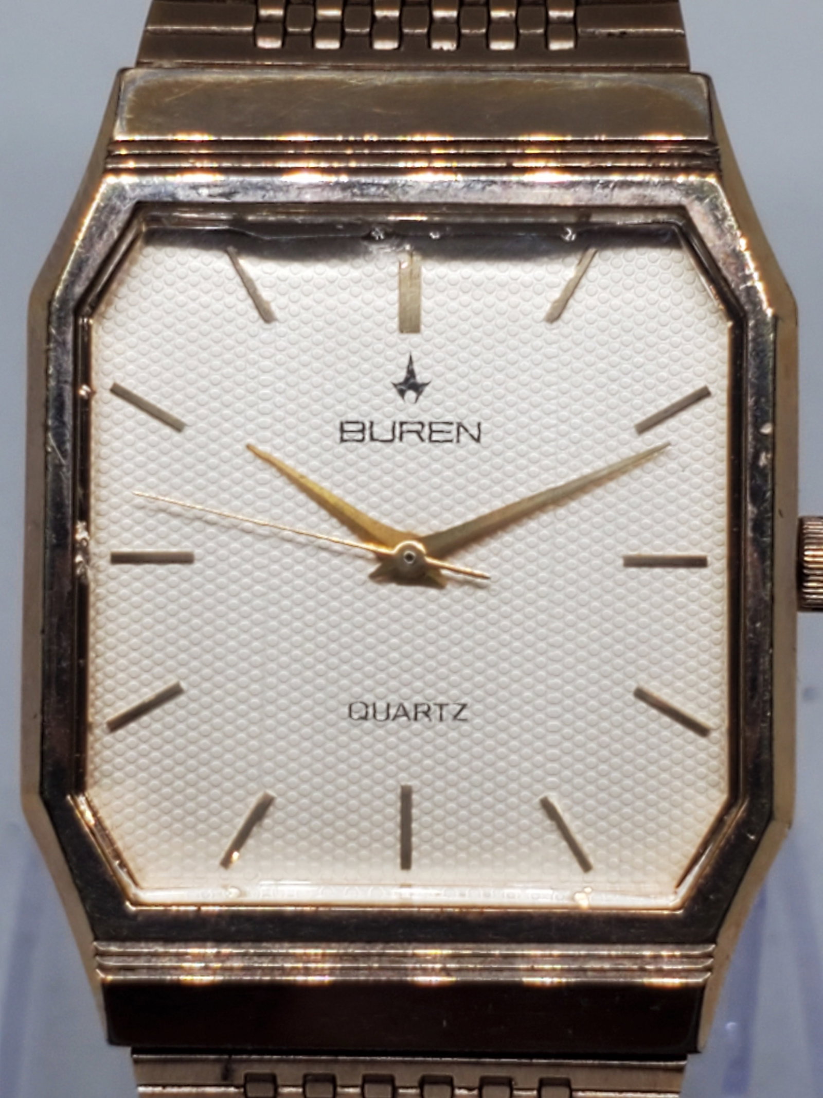 Vintage Buren Quartz Gold Tone Dress Watch Pattern Dial 27mm x 35mm, 1980s, Running: This vintage Buren quartz dress watch embodies elegance and timeless style with its gold tone case, patterned gold dial, and distinctive cut glass crystal. Its minimalist design and slim rectangular s