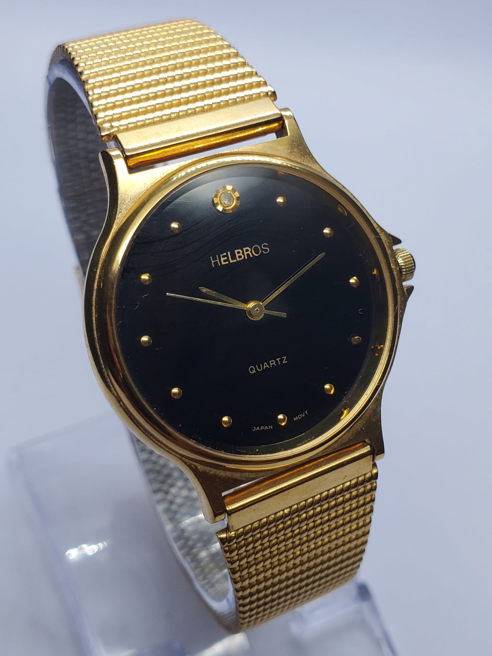 Vintage Helbros Diamond Black Dial Gold Tone Watch, 32mm, 1990s, Running: Elevate your collection with this elegant vintage Helbros Diamond quartz dress watch featuring a gold plated case, sophisticated black dial with gold tone markers, and a genuine diamond accent at the 