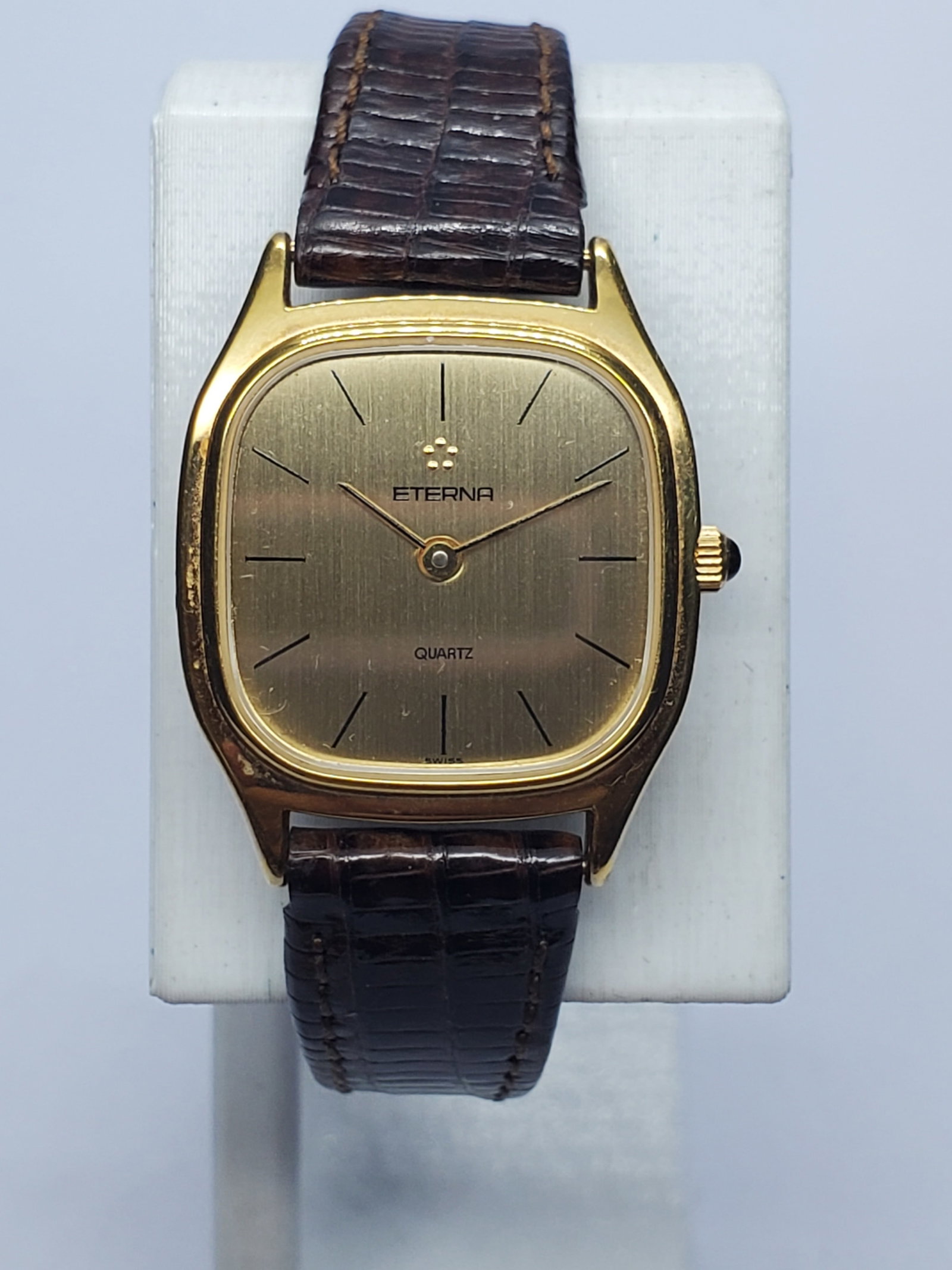 Vintage Eterna Gold Plated Quartz Watch, 23x23mm, 1980s, Running: This elegant vintage Eterna Model 121.6131.26 A ladies dress watch pairs a 23 x 23 mm gold-plated cushion case and refined gold dial with a 6.5-inch brown leather bracelet. Its Swiss quartz movement i