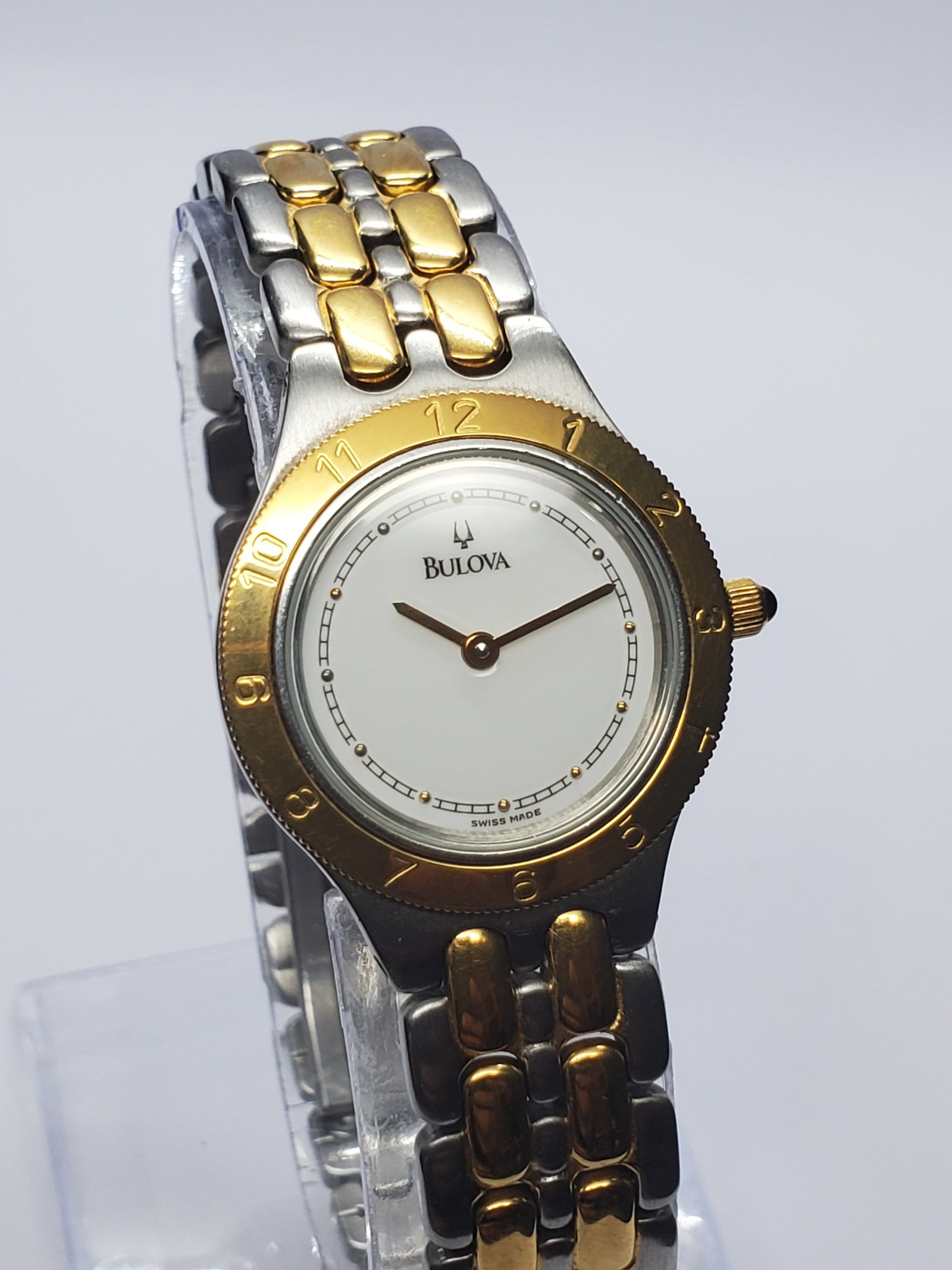 Vintage Bulova Dual Tone Dress Watch Gold Bezel, 25mm, 1990s, Running: Add timeless Swiss elegance to your collection with this Bulova 143 065 Quartz dress watch, a refined two tone timepiece that reflects the quality and prestige for which Bulova has been known for gene