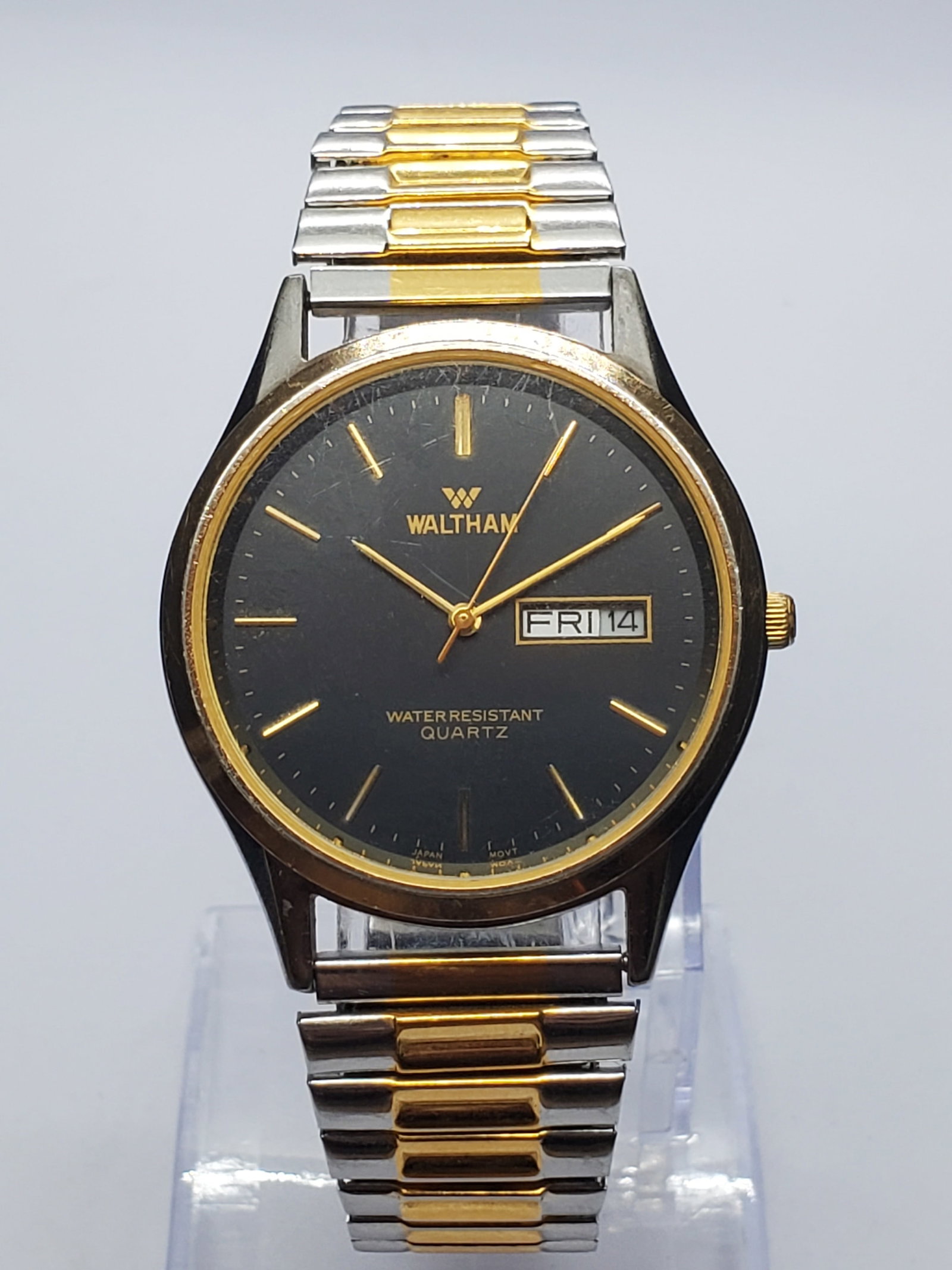 Vintage Waltham Black Dial Tone Watch, 35mm, 1990s, Running: Elegant vintage Waltham XC810 012 men?s dress watch featuring a 35 mm silver tone case, gold tone bezel, sophisticated black dial, gold baton markers, and practical day and date display. Its 7 inch ex