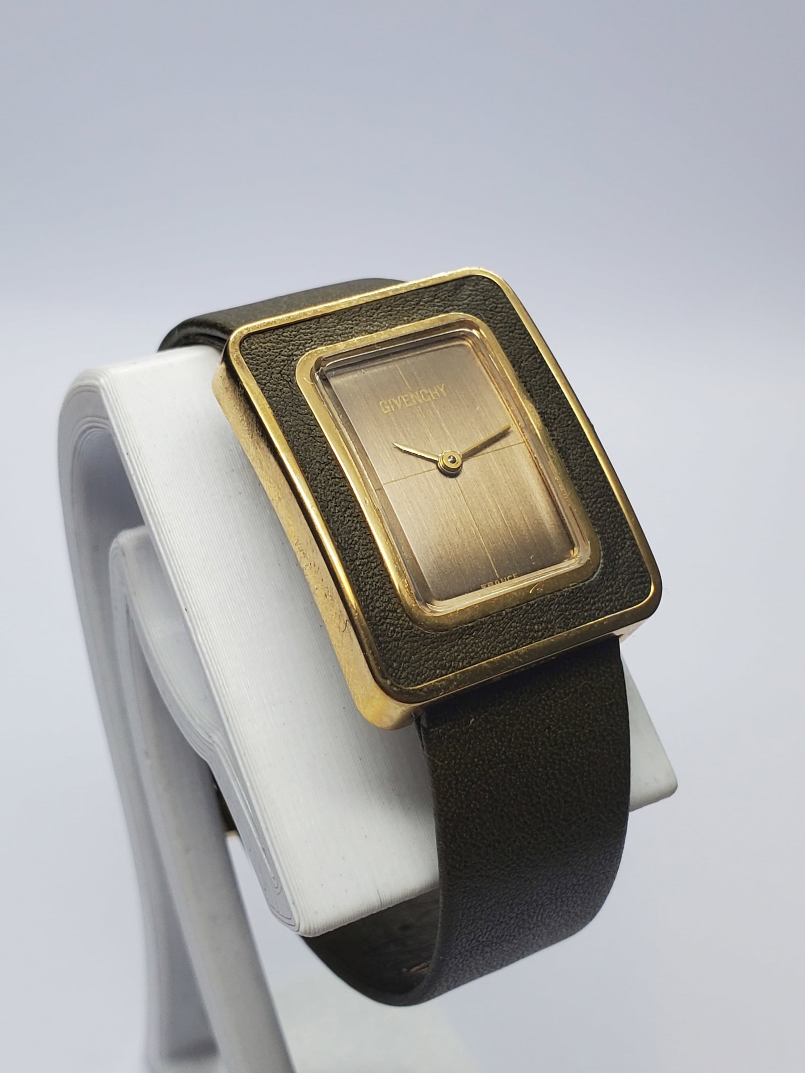 Vintage Givenchy Paris Manual Gold Plated Tank Watch, 22x28mm, 1970s, Running: Distinctive and elegant, this vintage Givenchy Paris manual-wind dress watch features a gold-plated rectangular case, richly textured brown bezel, minimalist brown dial, slender gold-tone hands, and a