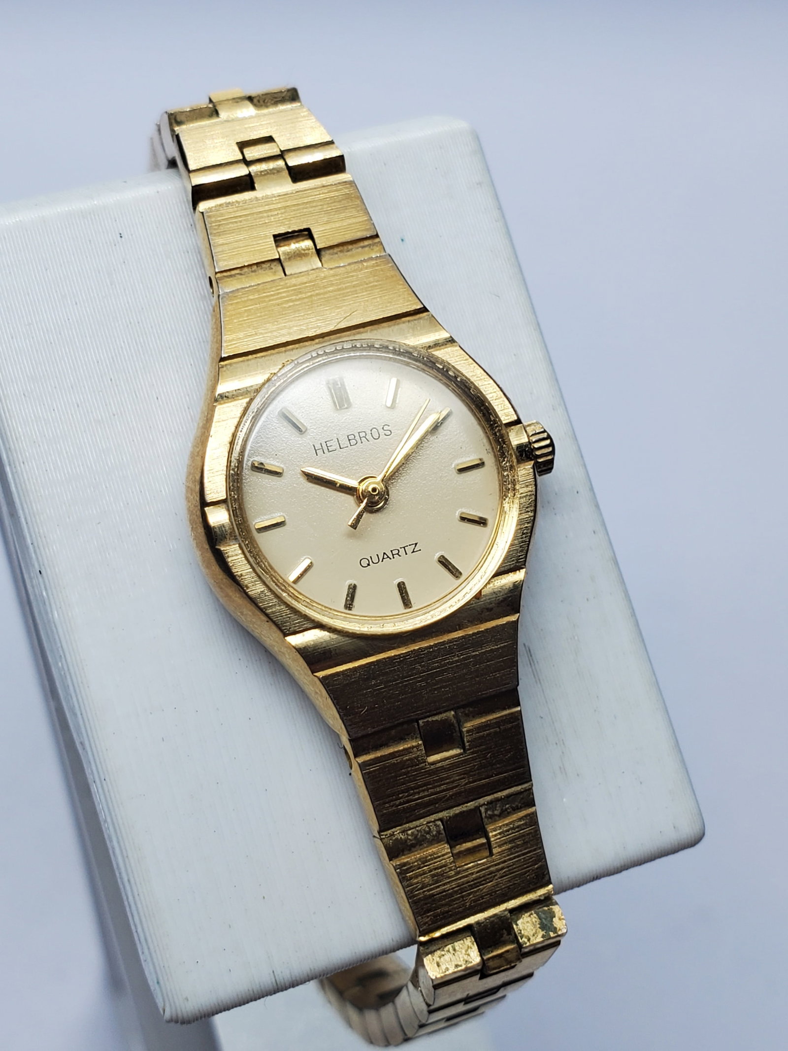 Vintage Helbros Gold Tone Dress Watch, 18x20mm, 1980, Running: Elegant and timeless, this vintage Helbros 4GB 86 4 Quartz Dress Watch features a refined gold tone case, matching gold tone dial, and original metallic bracelet measuring 6.25 inches. Its compact 18 