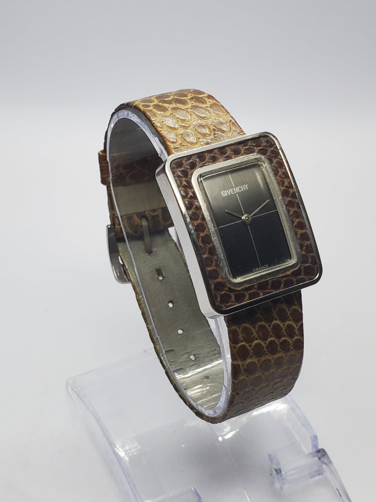 Vintage Givenchy Paris Manual Thank Watch, 22x28mm, 1970s, Running: Bold and sophisticated, this vintage Givenchy Paris manual-wind dress watch features a silver-tone rectangular case, richly textured brown leather bezel, minimalist black dial, slim silver-tone hands,