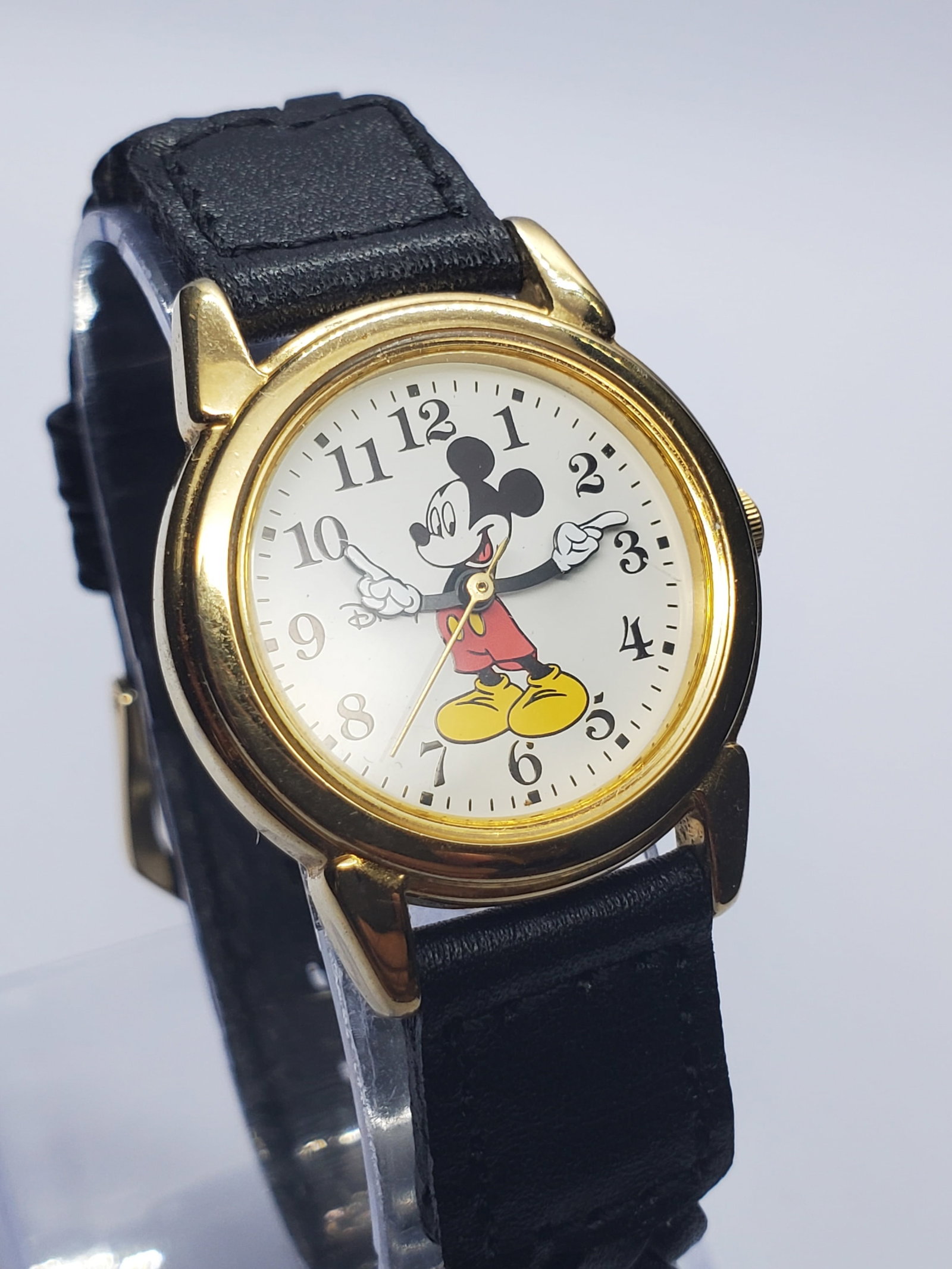 Vintage Disney SII Mickey Mouse Gold Tone Quartz Watch, 26mm, 1990s, Running: Celebrate timeless Disney charm with this vintage Disney SII RRS378 quartz dress watch featuring a gold plated case, crisp white dial, and the iconic Mickey Mouse character whose arms indicate the tim