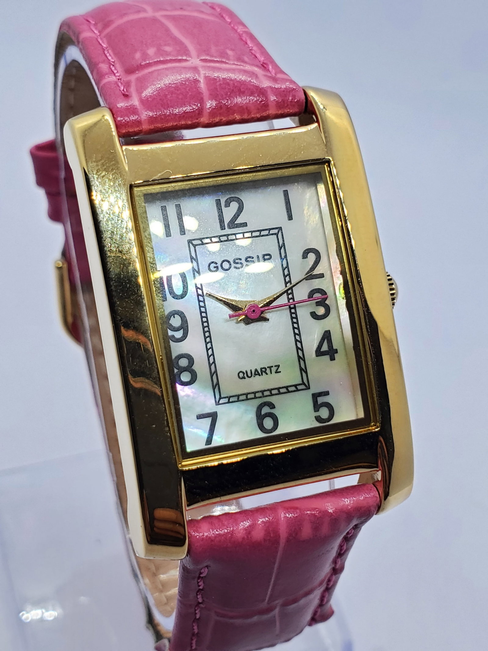 Vintage Gossip Gold Tone Tank Watch MOP Dial New in Box, 2005 to 20215, Running: This Gossip 173C quartz watch presents a refined dress style with a gold tone rectangular tank case 18 mm x 24 mm and an elegant mother of pearl dial accented by bold Arabic numerals and a contrasting