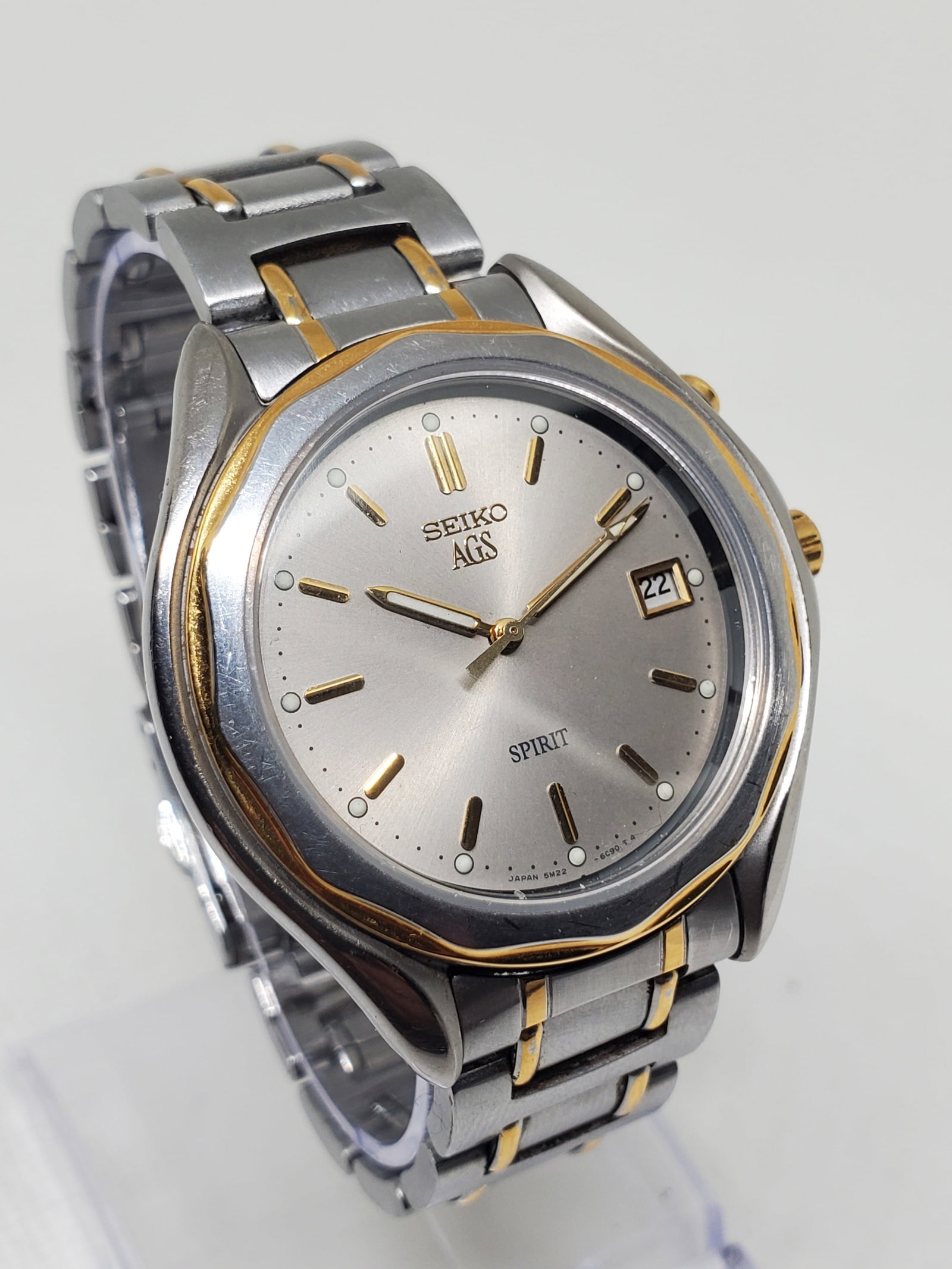 Vintage Seiko AGS Spirit Dual Tone 37mm Date Quartz Dress Watch, 1996 to 1999, Running: This Seiko AGS Spirit dress watch blends elegance and prestige with everyday reliability, showcasing a refined silver tone case with a dual tone bezel and a silver dial accented by gold markers and a 