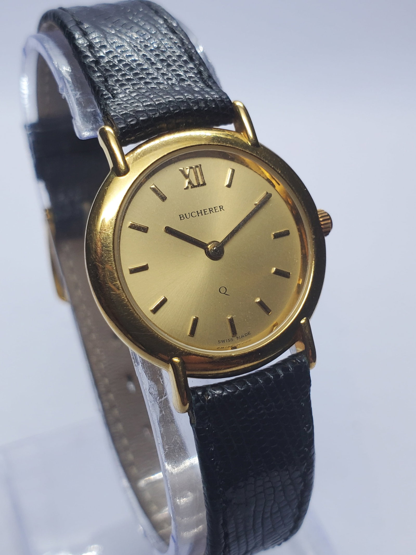Vintage Bucherer 127.500 Swiss Gold Plated Ladies Dress Watch,24mm , 1980s, Running: Discover timeless Swiss elegance with this vintage Bucherer 127.500 quartz dress watch featuring a refined gold plated case, gold tone dial with minimalist baton markers and Roman numeral at 12, paire