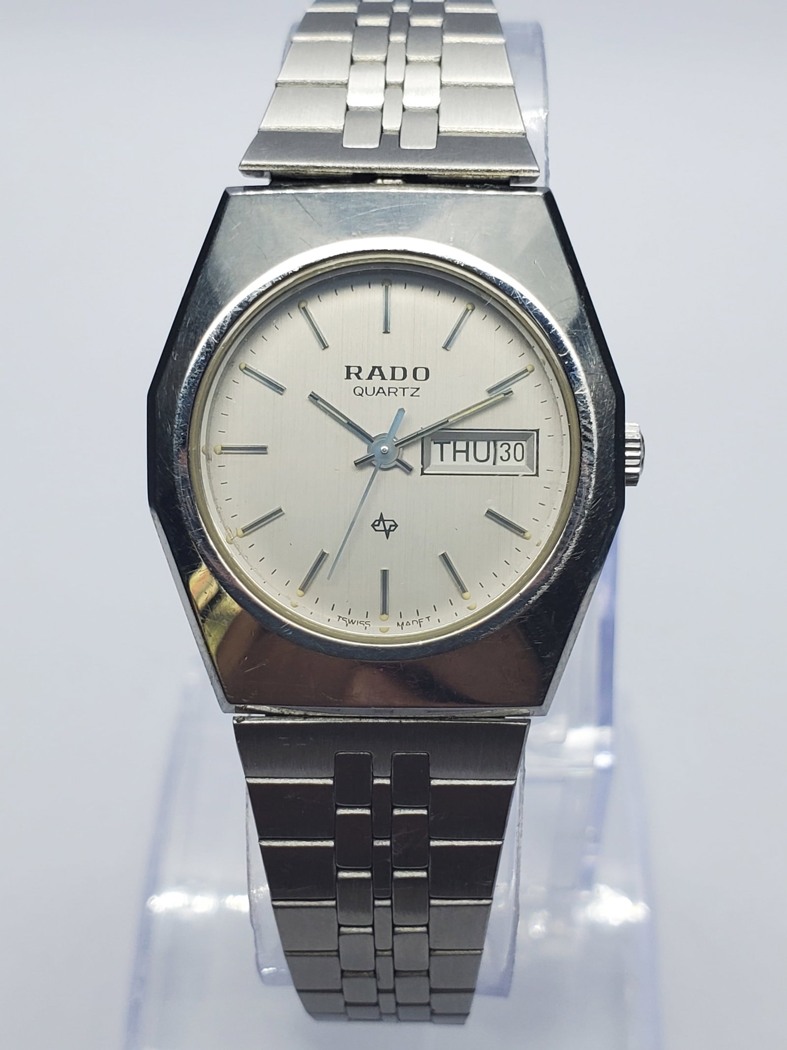 Vintage Rado Day-Date Swiss Dress Watch, 26x28mm, circa 1980, Running: Discover timeless Swiss elegance with this vintage Rado 123.3119.4 quartz dress watch, featuring a 26 x 28 mm silver-tone tonneau case, brushed silver dial, applied baton markers, central seconds, and