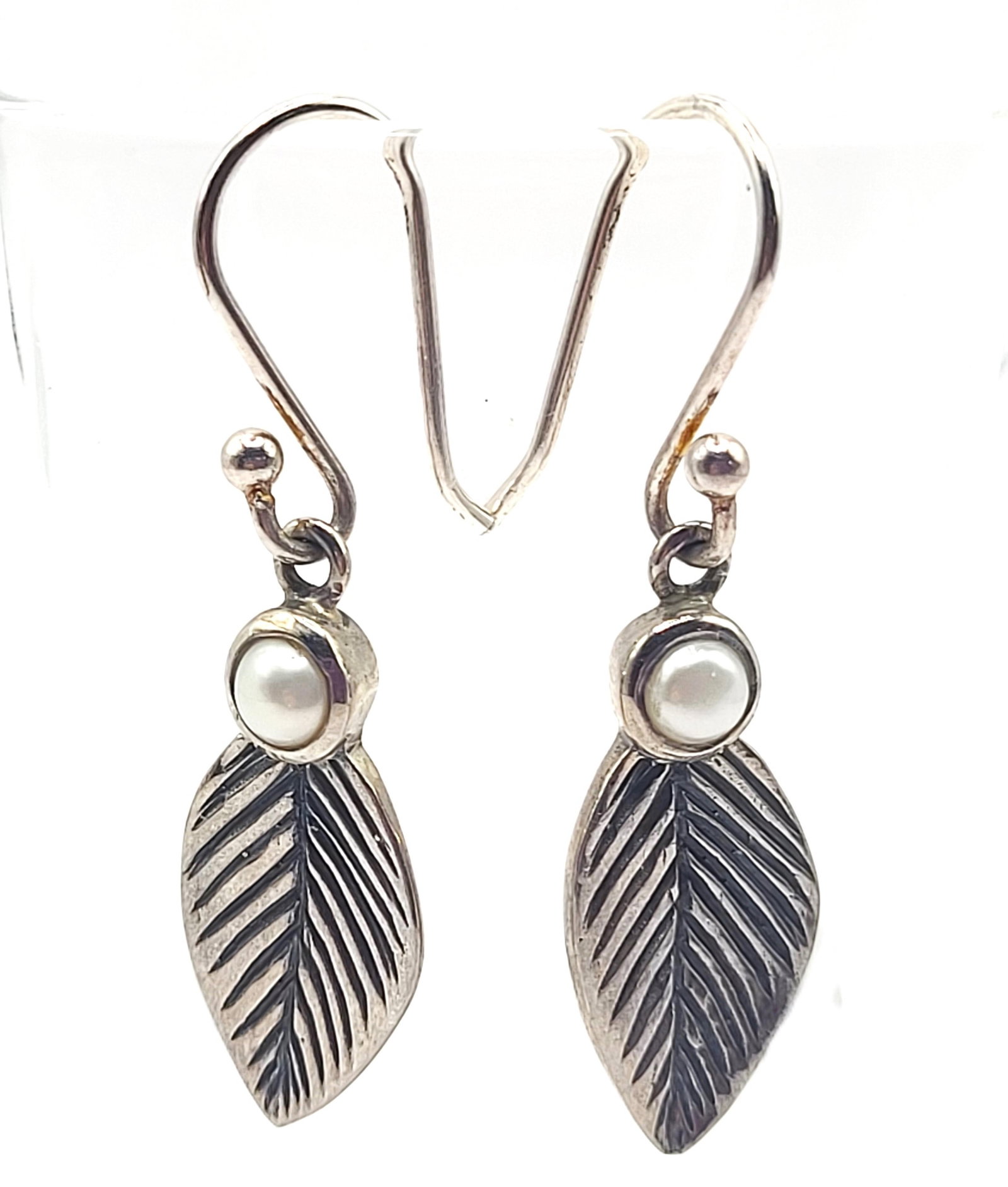 Dangling Leaf Earrings with Mabe' Pearl .925: Setting: Sterling Silver .925 Main Gemstone: Genuine Cultured Pearl Closure: Wire hooks The earrings go so well with the ring in Lot 22. These interesting earrings feature approximate 3.5-3.75mm bezel
