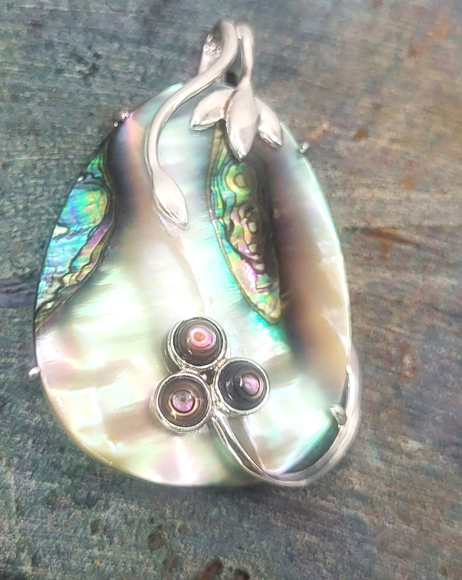 Abalone & Mother-of-Pearl Eggplant Unique Pendant: Setting: Sterling Silver .925 Primary Gemstone: Abalone Shell Secondary Gemstone: Mother-of-Pearl Dimensions: 1 3/4" x 1 3/8" What an organically original pendant! Carved from abalone shell with a