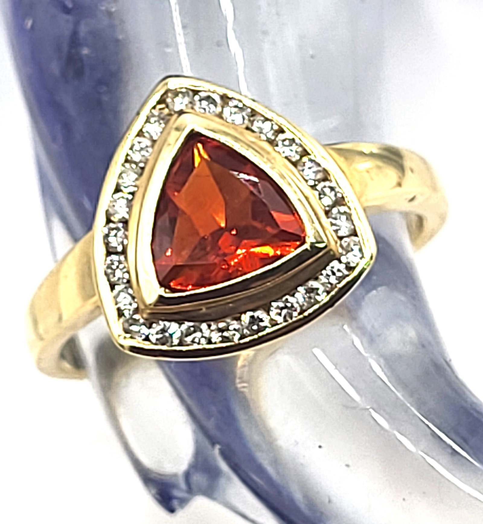 Trilliant-Cut Fire Opal with Diamond Halo Ring: Setting: 14K Yellow Gold Main Gemstone: Ge nuine Fire Opal Adjacent Gemstone: Genuine, Natural Diamond Size: US 6.5 Weight: 3g Fire opals can be pale orange to a blazing reddish-orange, like this one.