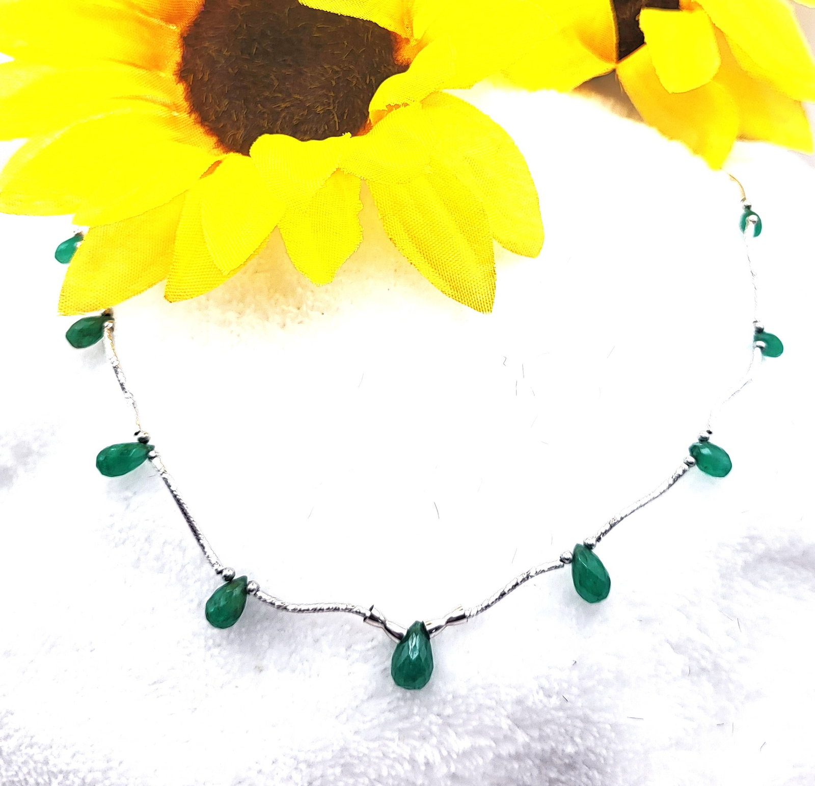 Briolette-Cut Emeralds & Delicate White Gold Ribbon Necklace: Setting: 14K White Gold Main Gemstone: Genuine Emerald Length: 18" Closure: Plunger-Style Bead Weight: 4.72g It is so light and delicate, it seems to float on your neck! This necklace is constructed w