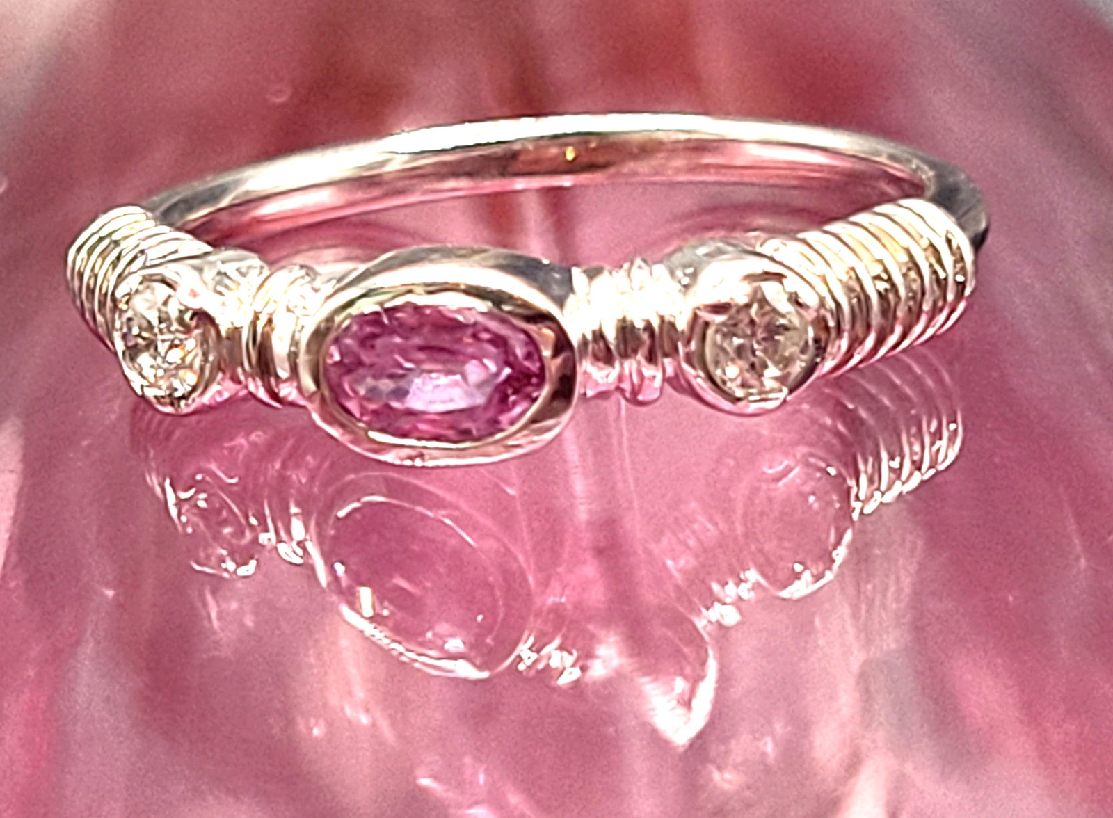 14K White Gold Pink Sapphire and Diamond Stacker Ring: Setting: 14K White Gold Main Gemstone: Genuine Pink Sapphire Adjacent Gemstone: Genuine Natural Diamond Size: 7 Weight: 3g Birthstone for: OCTOBER A .33 carat, oval-cut, bezel-set, genuine pink sapphi