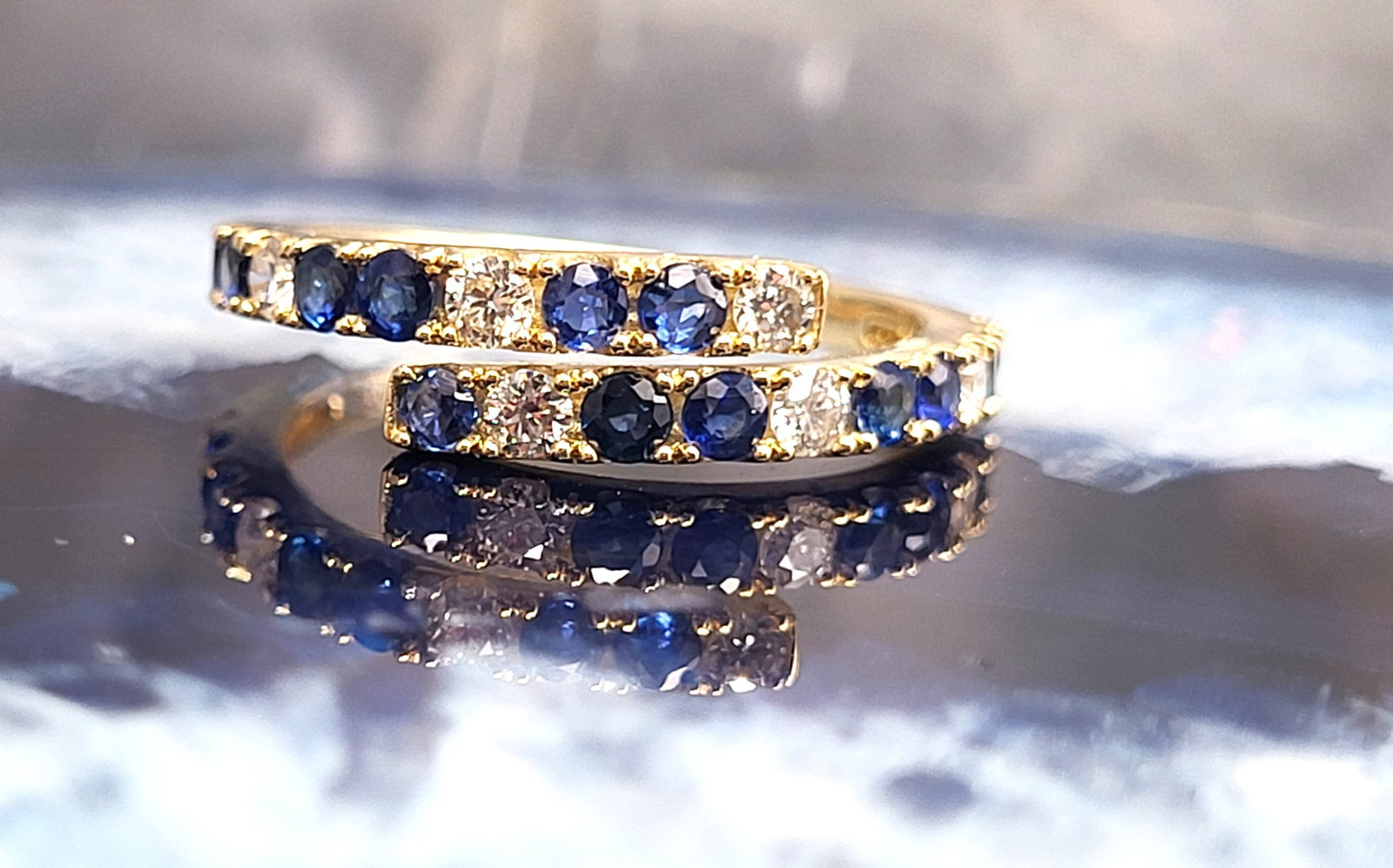 Breathtaking Blue Sapphire and Diamond Bypass Ring: Setting: 14K Yellow Gold Primary Gemstone: Genuine Blue Sapphire Secondary Gemstone: Genuine, Natural Diamond Size: 7 Weight: 3g The bypass ring has been a romantic design for over 100 years. Contempo