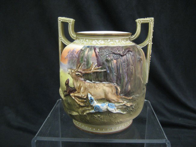 Nippon Green M with wreath 6 1/2" handled vase with: Nippon Green M with wreath 6 1/2" handled vase with molded deer being chased by dogs. Repair to left handle.
