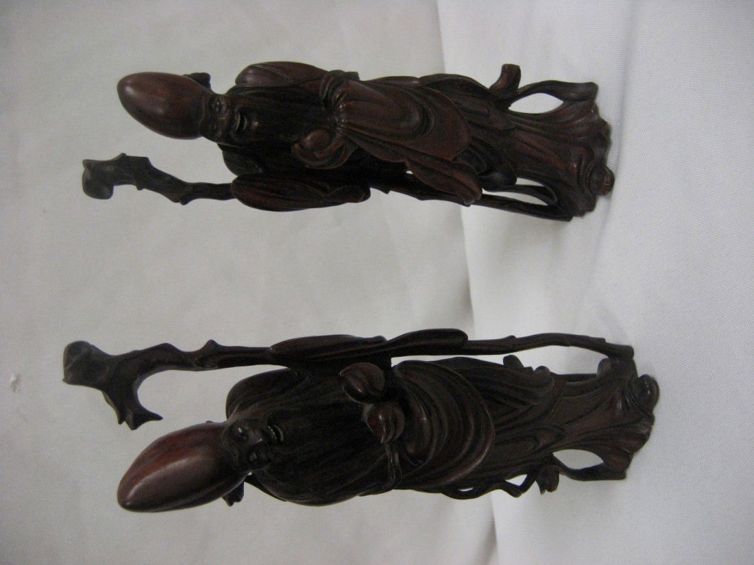 Pair of 7 3/8" carved iron wood figures holding st: Pair of 7 3/8" carved iron wood figures holding staffs and having inset eyes and teeth. Minor loss on portion of robe and minor separation at base on one figure