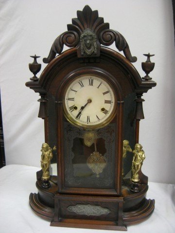 "Occidental" 8-day walnut parlor shelf: "Occidental" 8-day walnut parlor shelf clock with mirrored sides and brass statues, carved crest, turned finials and brass statues. Repair on crest, loss on finials, loss on right mirror at base. Mark