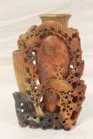 Carved black to cream to red/brown soapstone vase with: Carved black to cream to red/brown soapstone vase with carved flowers and leafy vine decoration. 10 1/8" tall, 6" wide.