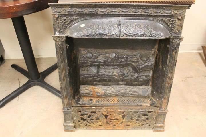 Cast iron fireplace insert with ornate molded columns: Cast iron fireplace insert with ornate molded columns and logs, w a mermaid at center top, winged putti at corners, and winged dragons or serpents on base plate. 25 3/8" wide at top, app. 30 1/2" tall