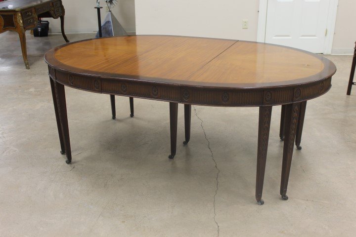 Oval mahogany marquetry top dining table with carved: Oval mahogany marquetry top dining table with carved apron with floral rosettes and bell flower carved tapered legs. Banded top witn inlaid band. App. 79 3/4" long, 50 1/4" wide, 29 1/2" tall. Veneer 