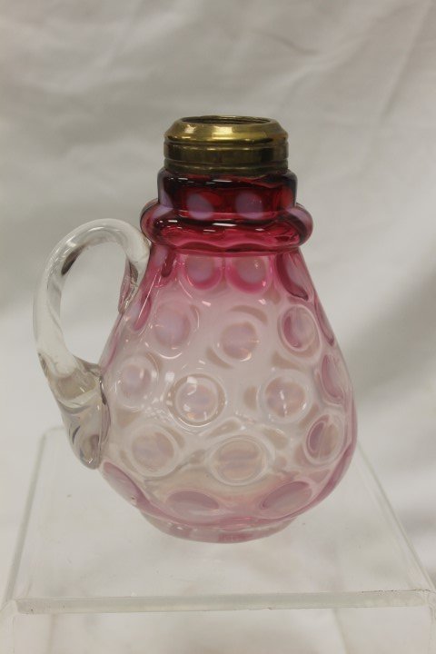 Clear to cranberry coin dot opalescent syrup with brass: Clear to cranberry coin dot opalescent syrup with brass fitter for an oil lamp. 6 1/8" tall, straw marks in glass, flake at rim