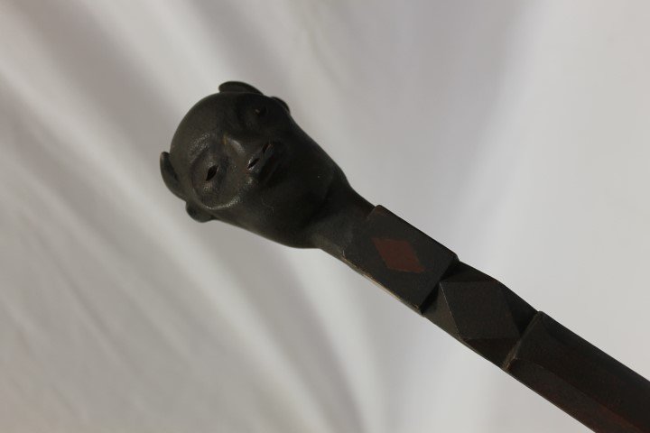 Folk art carved cane with carved goat head over a block: Folk art carved cane with carved goat head over a block inlaid with two red diamonds and bon full and quarter moons, over a diamond cut block on a tapered octagonal shaft. App. 35" long.