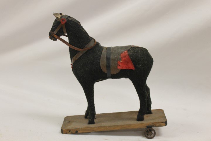 Early horse pull toy with burlap body, leather tack: Early horse pull toy with burlap body, leather tack, ears and saddle, glass eyes. No tail or mane, missing front wheels, 9 1/2" tall, 8 3/4" long, 2 5/8" wide
