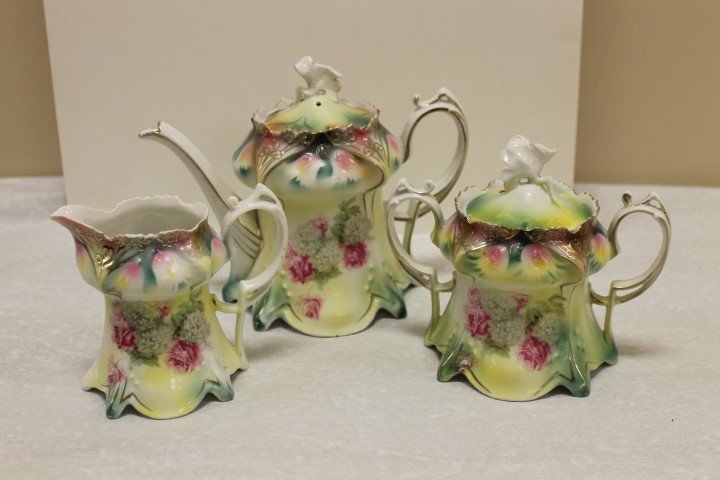Red mark RS Prussia 3 pc. Tea set with floral: Red mark RS Prussia 3 pc. Tea set with floral decoration. Finial damage on lid to teapot, repaint chip on rim of teapot; interior rim flake on creamer, chips around base; sugar lid is a mismatch by de