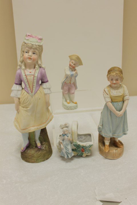 Bisque grouping: 4 1/4" French basket with holly; 5: Bisque grouping: 4 1/4" French basket with holly; 5 1/2" rosy cheek boy; 8 3/4" pleasant young lady; 11 1/2" figure of a young lady with minor base nicks.
