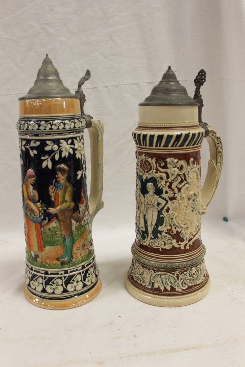 (2) German steins: 2 1/2L with kissing putti on sides: (2) German steins: 2 1/2L with kissing putti on sides and young boy and girl holding hands on front, 15" tall, #249 and 9 on base; lustre finish 2L stein with man with pipe and lady with basket of fru