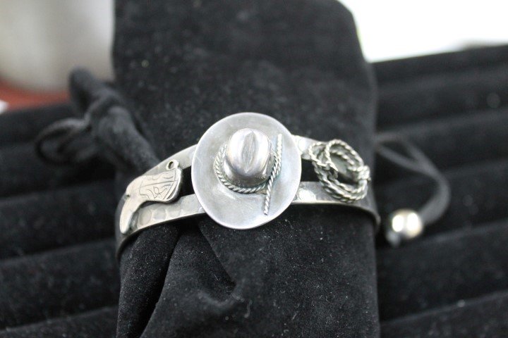 Hammered silver cuff bracelet with cowboy hat: Hammered silver cuff bracelet with cowboy hat, boot and lariat on marked sterling cuff.