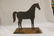 Mounted sheet iron horse on wooden base, with strap at - 2