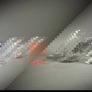 FOUR GLASS BEAKER AND A HANDLED BEAKER: FOUR GLASS BEAKER AND A HANDLED BEAKERmostly 19th centuryH. 9,5/12 cmColourless cut glass, one partially red glazed. Chips.Vier Bechergläser und Henkelglasmeist 19. Jhdt.H. 9,5/12 cmFarbloses