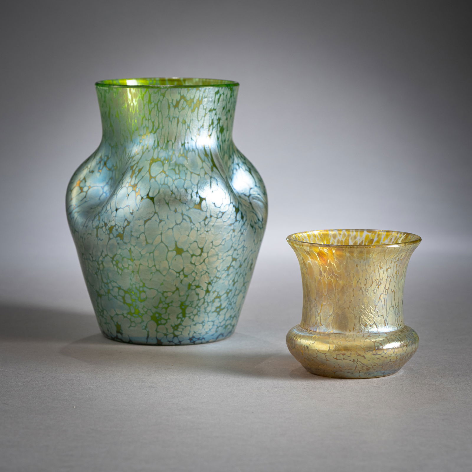 TWO PAPILLON PATTERN LOETZ VASES: TWO PAPILLON PATTERN LOETZ VASESLoetz Wwe., Klostermühle, ca. 1900H. 9/15,5 cmGreen or colourless glass with melted silver crumbs, the small one slightly abraded at the rim.Zwei Vasen mit Papillo